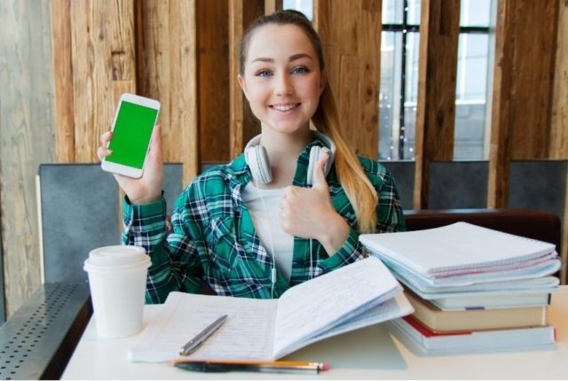 スマホを片手にサムズアップする女性